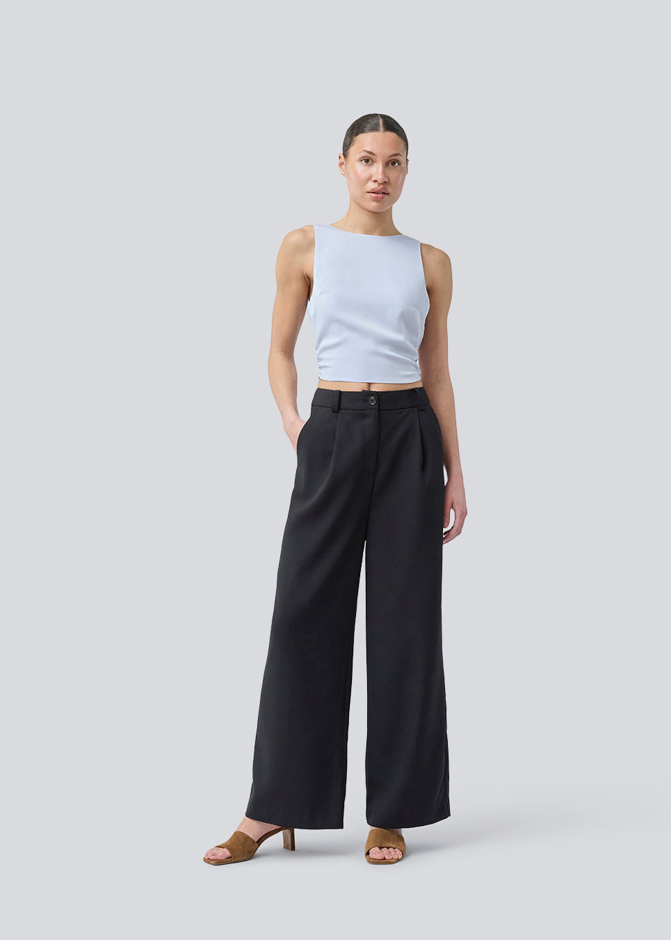 Ærmeløs top i satin i lysegrålig blå. TailorMD top har en åben ryg som lukkes med et bindebånd. Modellen er 177 cm og har en str S/36 på.