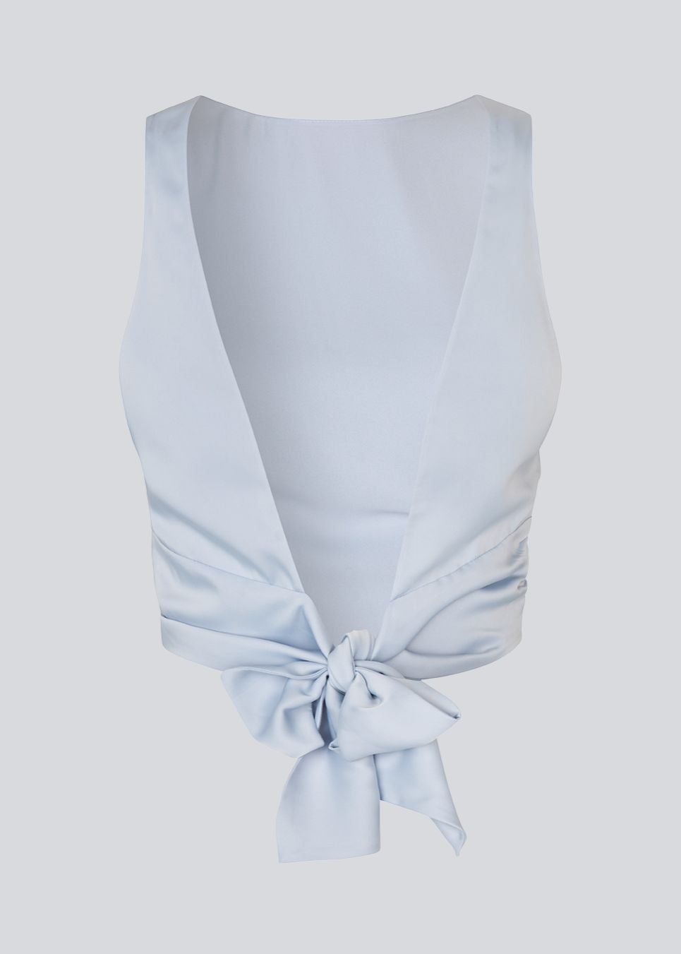 Ærmeløs top i satin i lysegrålig blå. TailorMD top har en åben ryg som lukkes med et bindebånd. Modellen er 177 cm og har en str S/36 på.