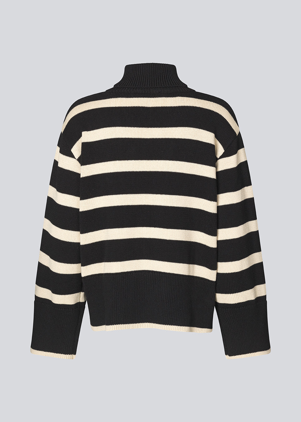 Finstrikket, oversized trøje i bomuldsstrik i sort med beige striber. CorbinMD stripe t-neck har en ribstrikket rullekrave, lange brede ærmer og brede ribkanter ved ærmer og forneden. Modellen er 177 cm og har en størrelse S/36 på.