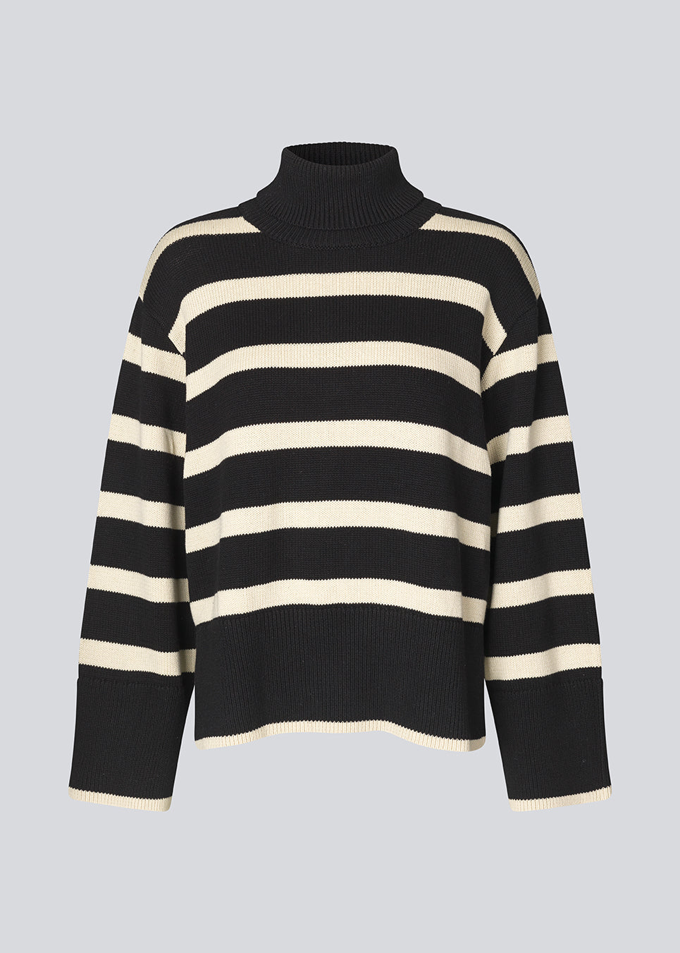 Finstrikket, oversized trøje i bomuldsstrik i sort med beige striber. CorbinMD stripe t-neck har en ribstrikket rullekrave, lange brede ærmer og brede ribkanter ved ærmer og forneden. Modellen er 177 cm og har en størrelse S/36 på.