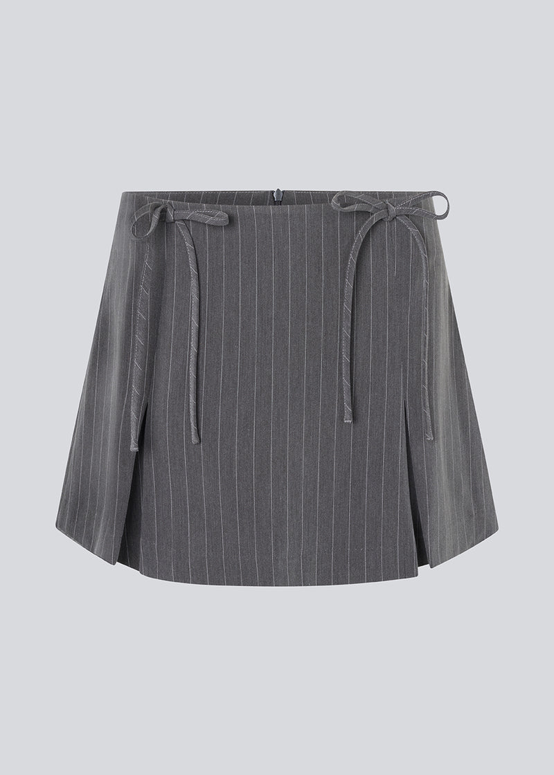 Kort nederdel i grå med sløjfer og læg. EmiliaMD bow skirt har en usynlig lynlås bagpå og to fine sløjfedetaljer foran.&nbsp;