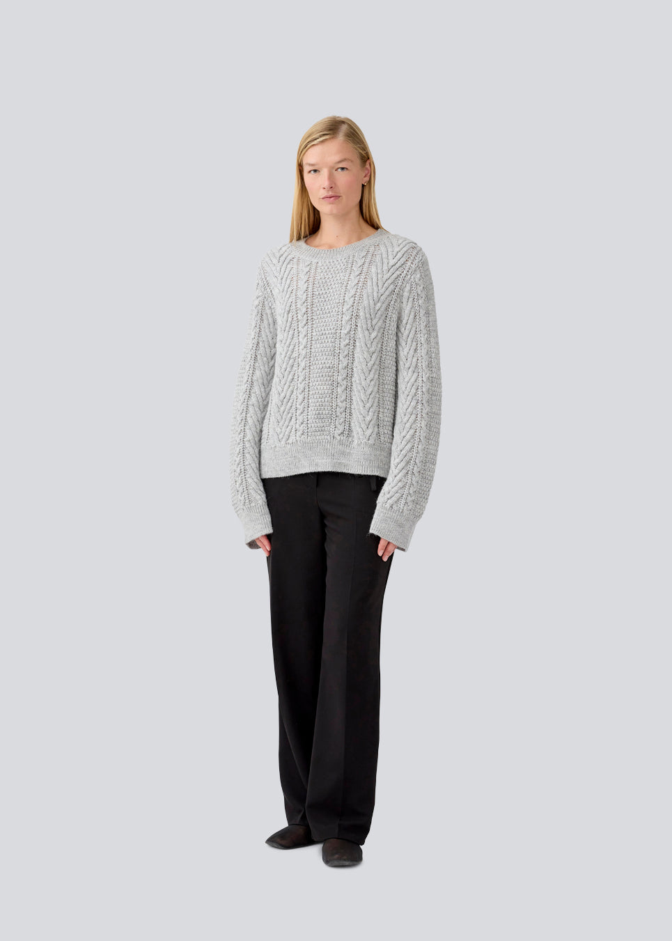 Kabelstrikket grå trøje i kvalitet med uld. GrannonMD o-neck har en afslappet pasform med lange ærmer og rund hals, med ribkant ved hals, ærmer og forneden. Modellen er 175 cm og har en størrelse S/36 på.