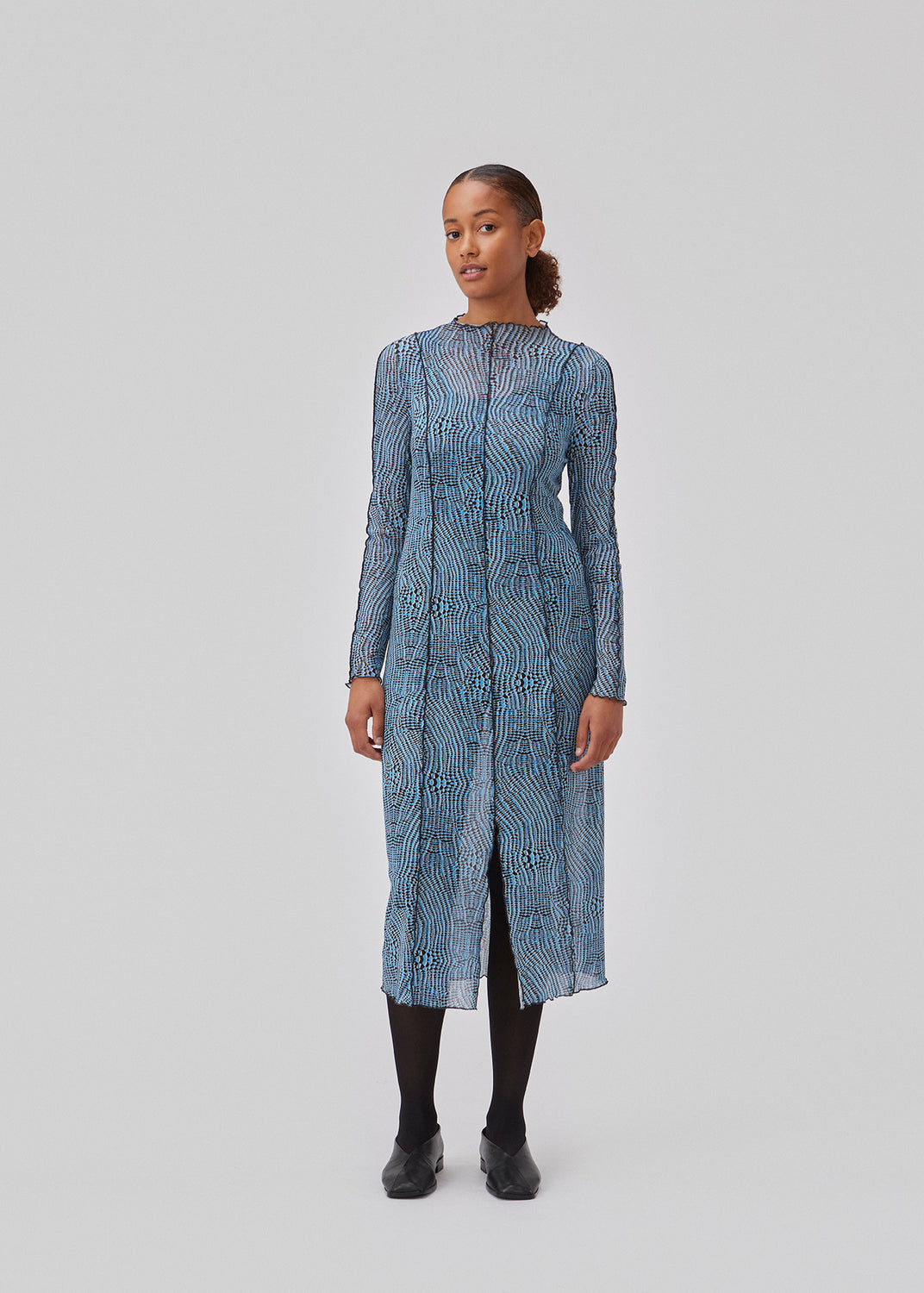 Kjole i mesh med høj hals, lange ærmer og midi længde. GwenMD print dress har dekorative bølgekanter på krop, hals og ærmer. Kjolen har slids foran og er en smule transparent. Modellen er 175 cm og har en størrelse S/36 på.