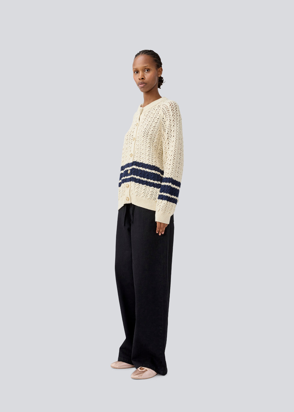 Løs strikket cardigan i beige med mørkeblå striber i kabel strik. MetteMD cardigan er let gennemsigtig, har løse ærmer og en knappelukning fortil. Modellen er 177 cm og har en str. S/36 på.