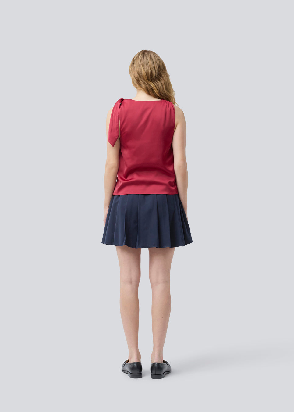 Kort nederdel med læg og mellemhøj talje i mørkeblå. Peggiemd skirt har en usynlig lynlås i siden. Modellen er 175 cm og har en str S/36 på.