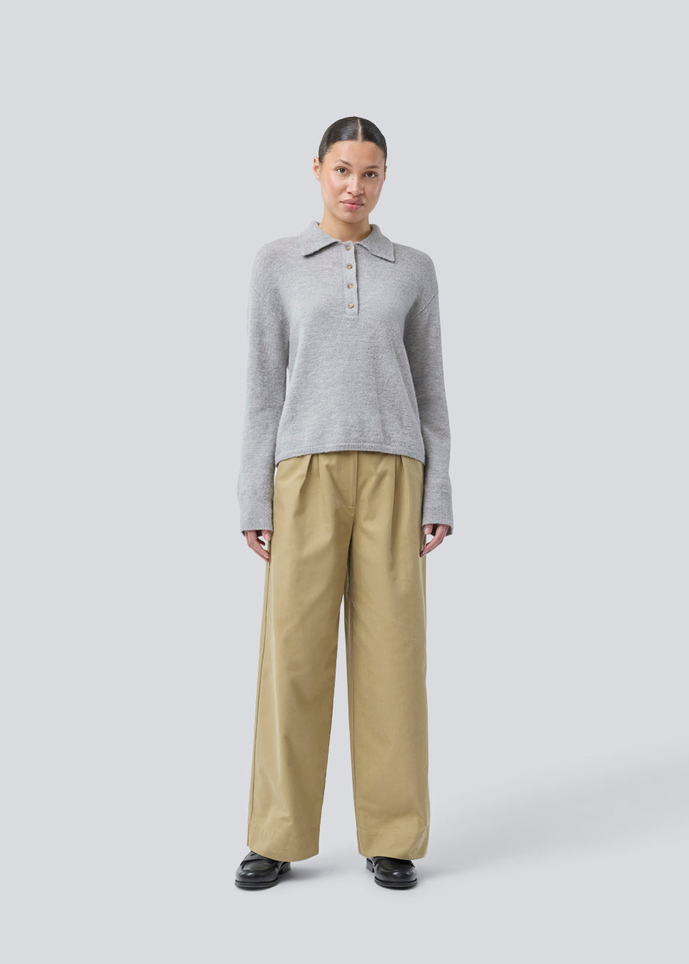 Strikket polo i grå med lange brede ærmer. Treemd polo har en stolpelukning og 4 knapper. Modellen er 175 cm og har en str. S/36 på.