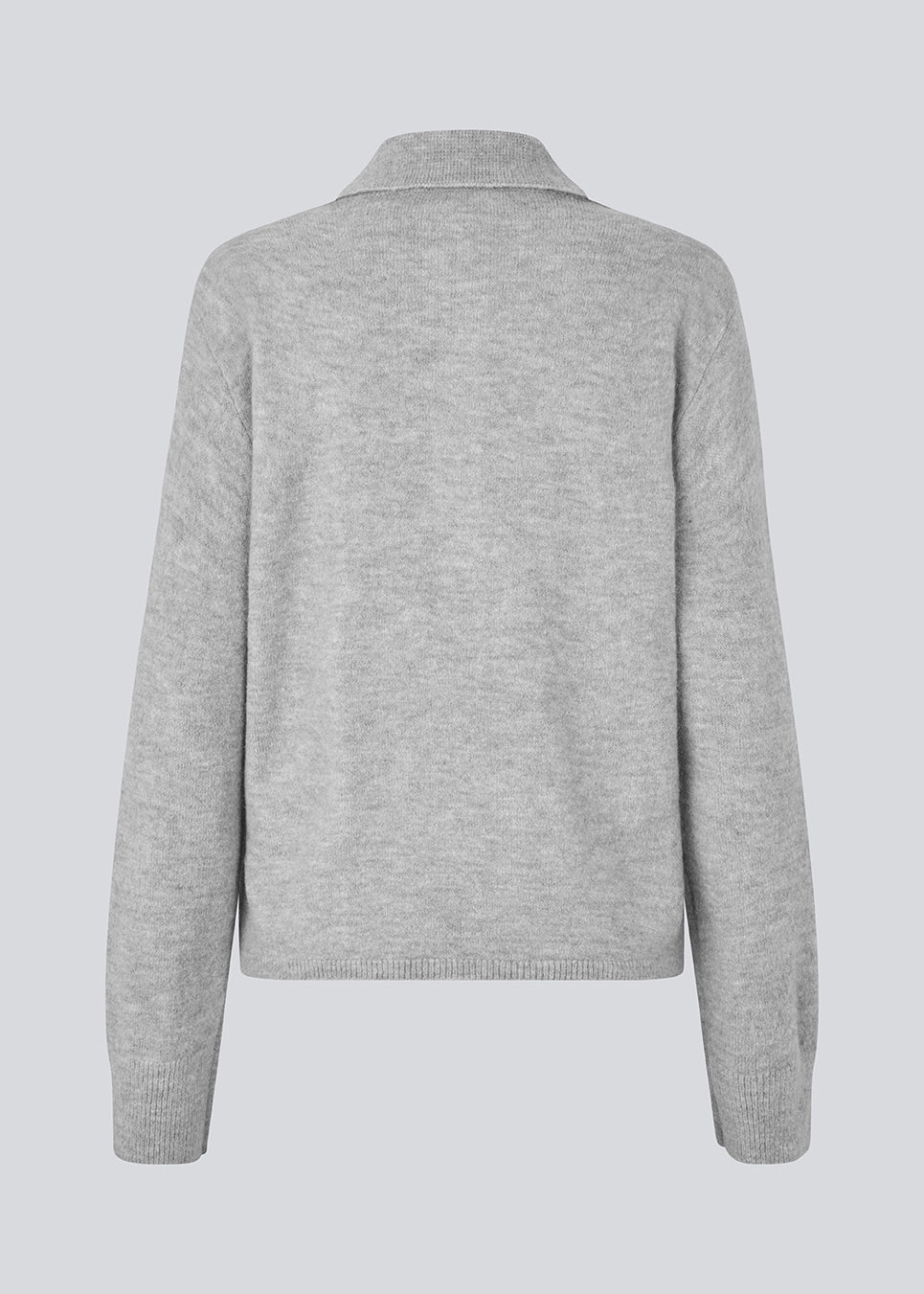 Strikket polo i grå med lange brede ærmer. Treemd polo har en stolpelukning og 4 knapper. Modellen er 175 cm og har en str. S/36 på.