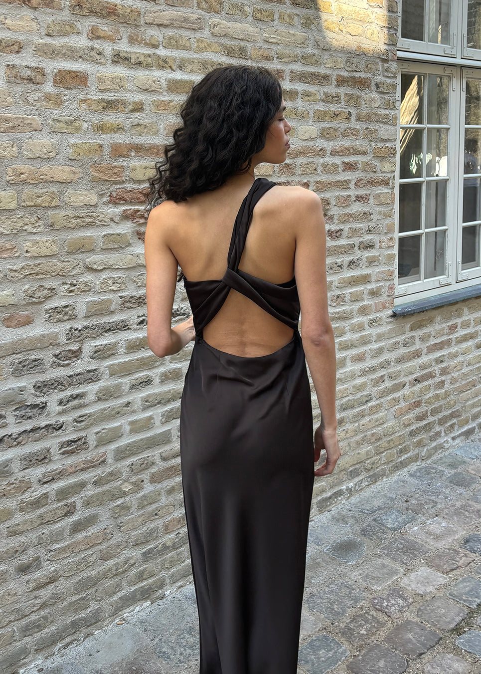Vores populære Narcissamd dress er nu endelig kommet i en flot mørkebrun.
Mørkebrun lang one shoulder kjole i satin. NarcissaMD dress er en maxi dress med en åben ryg med smukke detaljer og en usynlig lynlås i siden.
