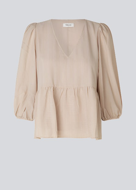 Top i beige i løs silhuet med 3/4 lange pufærmer, v-udskæring i halsen og en skæring i taljen, der giver ekstra volumen på den nederste del af toppen.