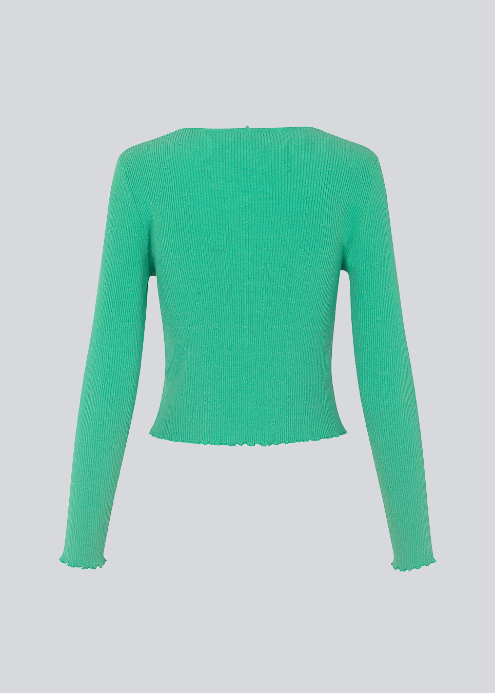 Tætsiddende, let cropped cardigan i grøn med knaplukning foran. DorisMD cardigan har en dybrund halsudskæring, lange ærmer og bølgekanter i bund og ved manchet. Modellen er 177 cm og har en størrelse S/36 på.