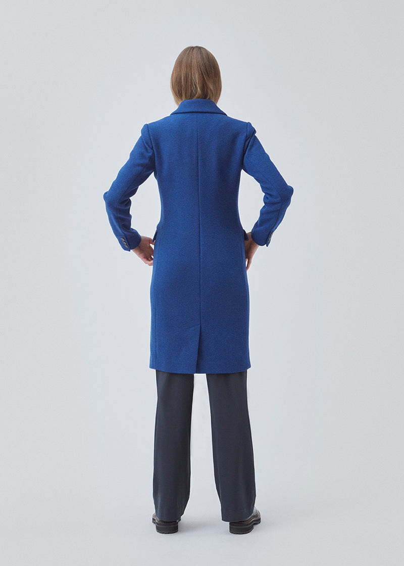 Smuk knælang uldfrakke i flot blå. Pamela coat bliver knappet fortil af 3 store knapper og er taljeret, som giver et feminint udtryk. På grund af den høje kvalitet af uld, vil den være det oplagte valg at bruge til både efterår og de milde vintre.