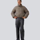 Let cropped puffer i en brunlig farve med høj hals. JoniMD jacket har to sidelommer, elastik i bunden af ærmerne og et justerbar snører i bunden.