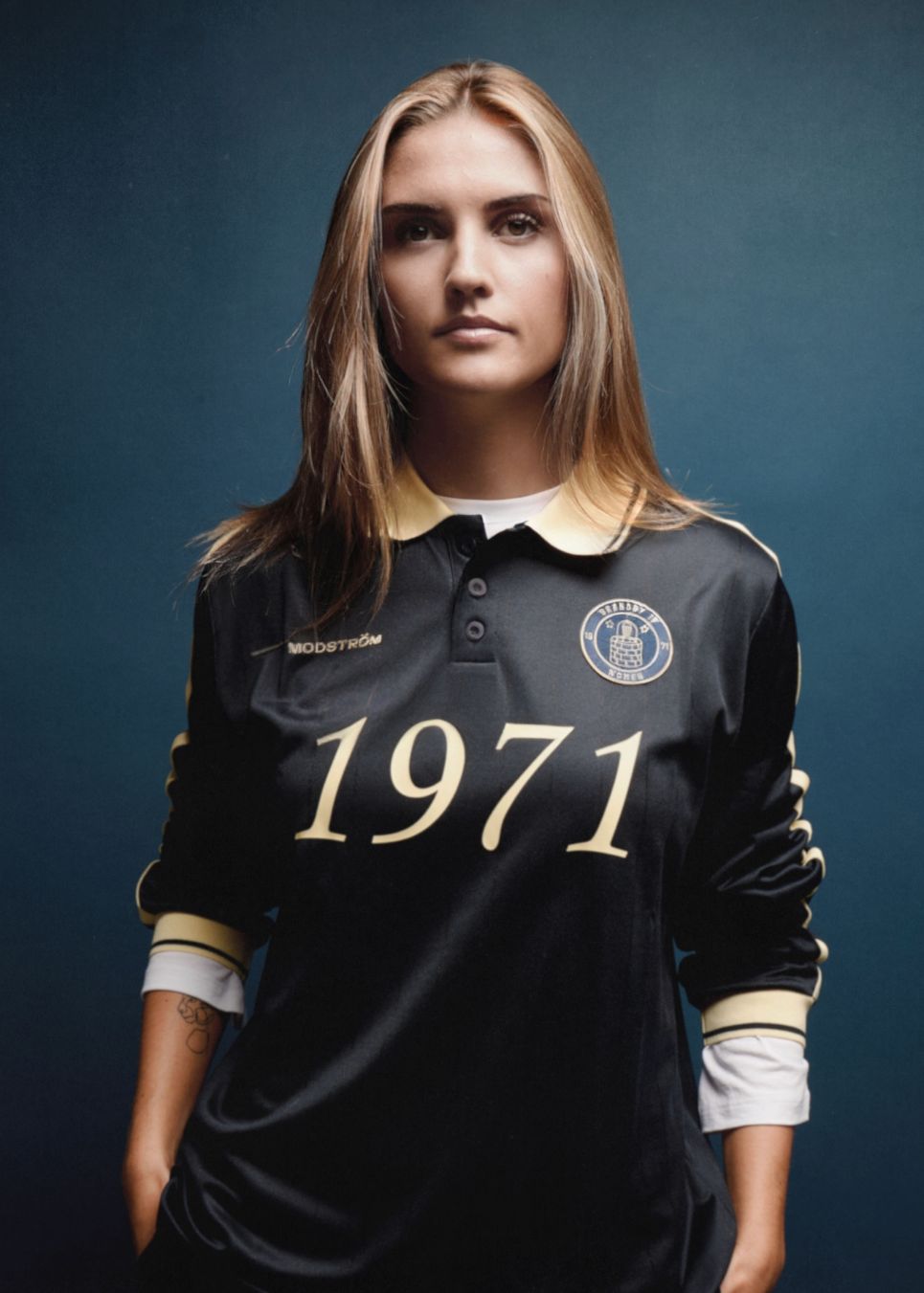 Fodbold jersey i mørkeblå med gule detaljer lavet i samarbejde med Brøndbys kvindehold. 1971 Polo har en løs pasform med stolpelukning og krave, samt lange ærmer med ribkant. Desuden har poloen Brøndby Womens og Modström logo på brystet.