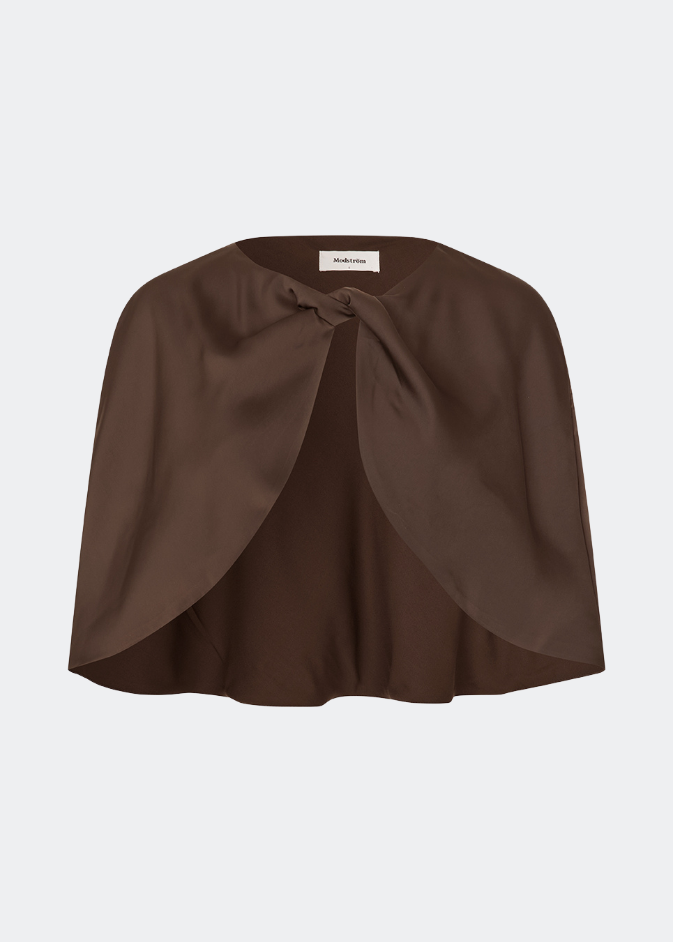 Tailormd Cape er en elegant satin-cape, der tilfører et raffineret og dramatisk udtryk til ethvert outfit. Designet falder let over skuldrene og lukkes foran med en dekorativ knudedetalje, som skaber et blødt, flydende fald. Brug den over en kjole til særlige anledninger eller som et eksklusivt lag over en enkel top for et sofistikeret look. Modellen er 175 cm høj og bruger størrelse S/36.