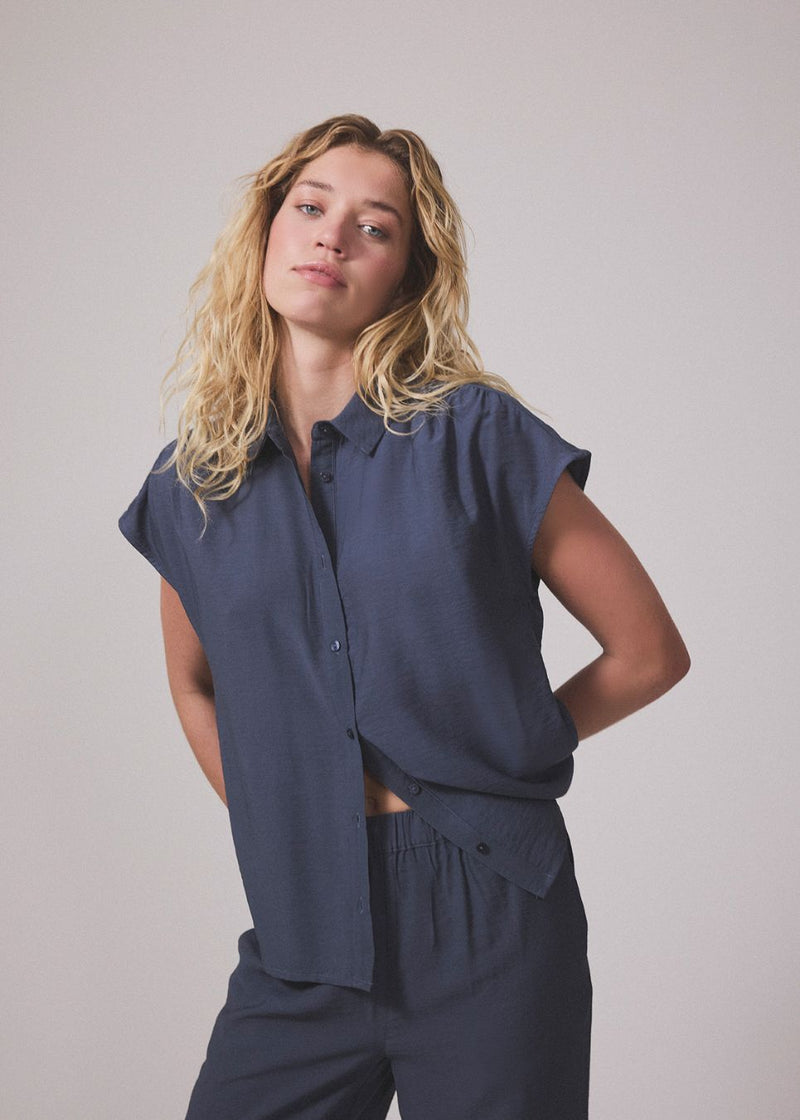 Ærmeløs skjorte i blå med knappelukning fortil i EcoVero viscose. NickiMD SS shirt har en løs pasform en rynkedetalje ved skulderen.