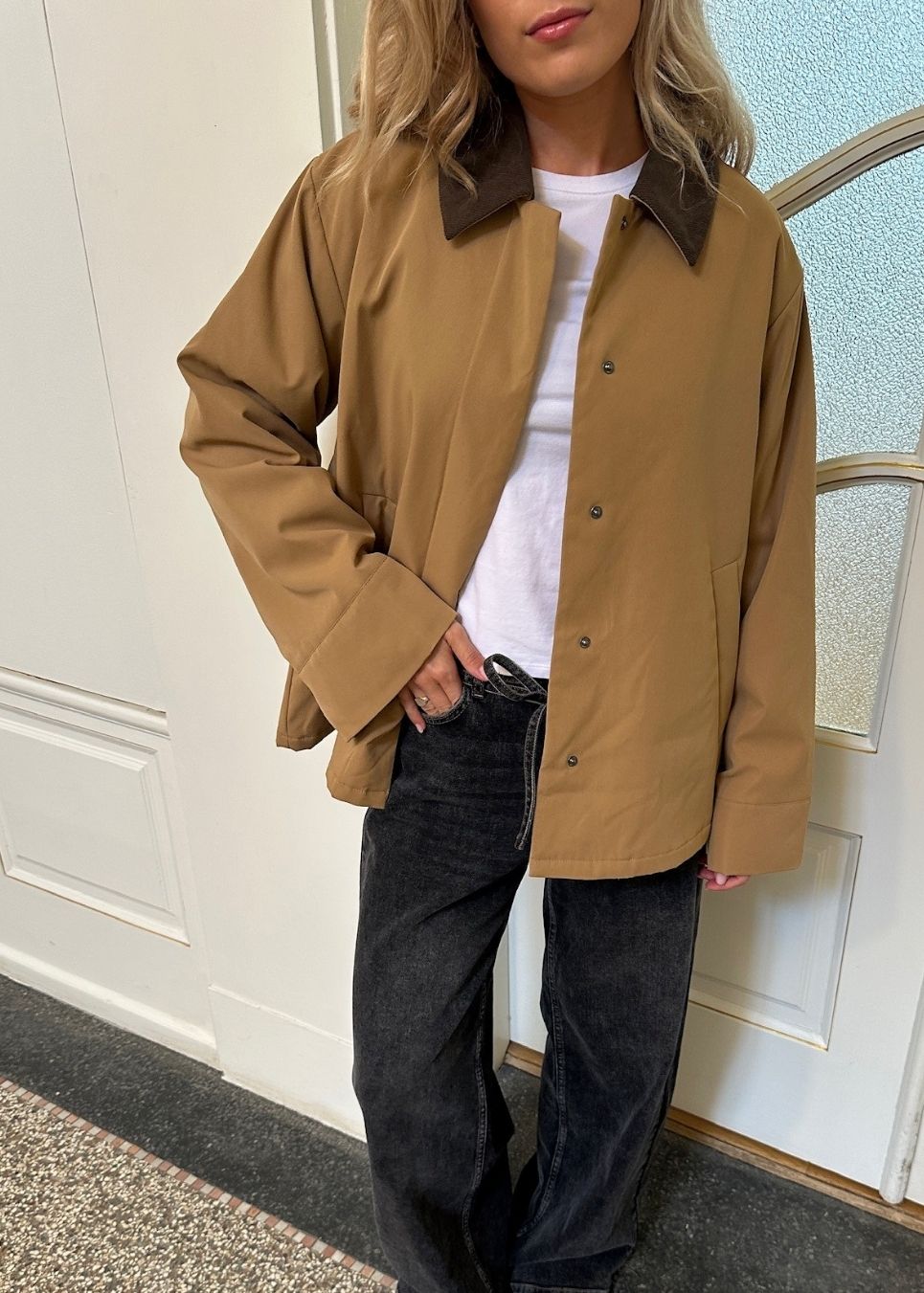 Løs jakke i beige med kontrast fløjlskrave i mørkebrun og skjult knappelukning. Orkidemd jacket har læg på rykken.