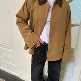 Løs jakke i beige med kontrast fløjlskrave i mørkebrun og skjult knappelukning. Orkidemd jacket har læg på rykken.