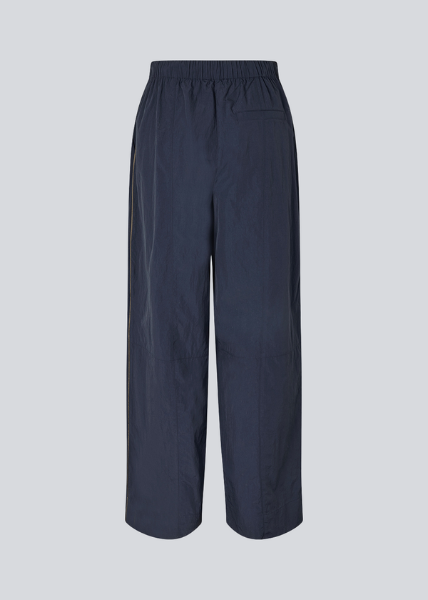Mørkeblå tracksuit pants i 100% genanvendt nylon. Volmermd pants har piping lang sidesømmen samt cutline detaljer for et sporty look.