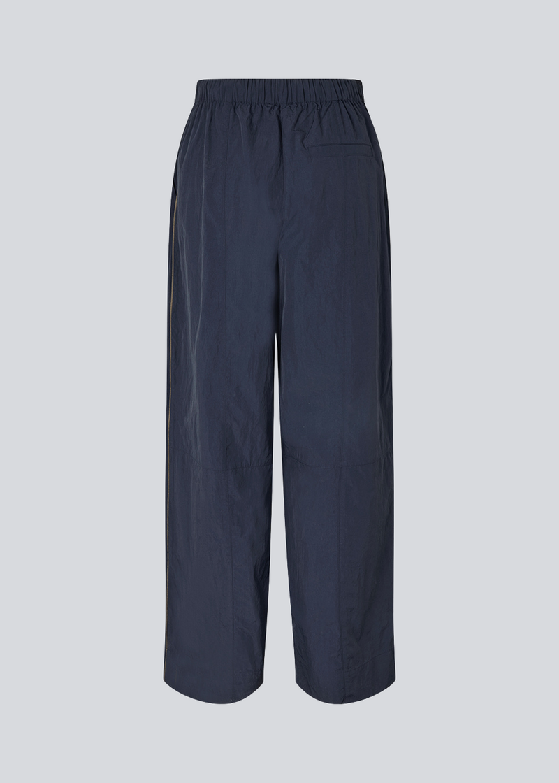 Mørkeblå tracksuit pants i 100% genanvendt nylon. Volmermd pants har piping lang sidesømmen samt cutline detaljer for et sporty look.