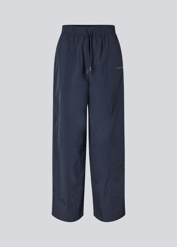 Mørkeblå tracksuit pants i 100% genanvendt nylon. Volmermd pants har piping lang sidesømmen samt cutline detaljer for et sporty look.