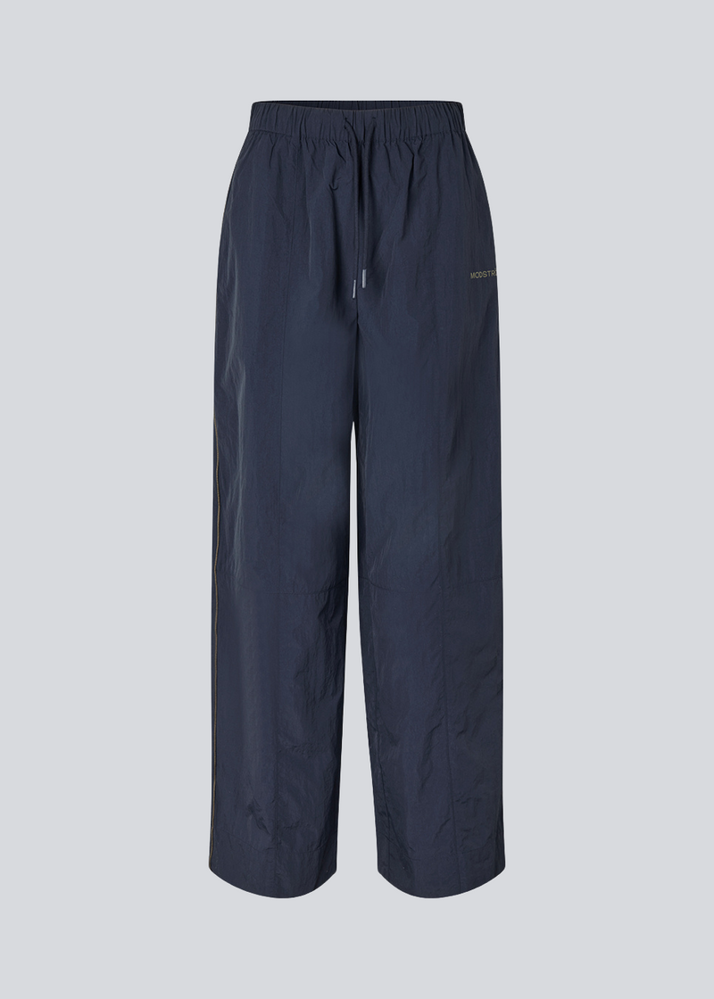 Mørkeblå tracksuit pants i 100% genanvendt nylon. Volmermd pants har piping lang sidesømmen samt cutline detaljer for et sporty look.
