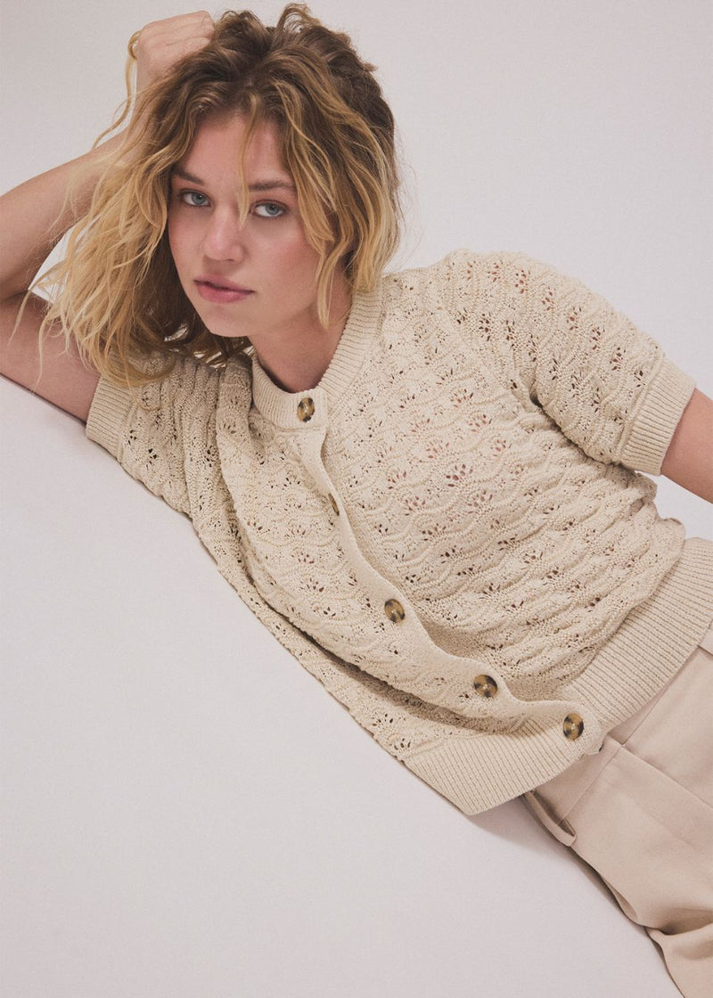 Kortærmet beige cardigan i strik med pointelle mønster. NeppoMD cardigan har en løs pasform og en knappelukning fortil.
