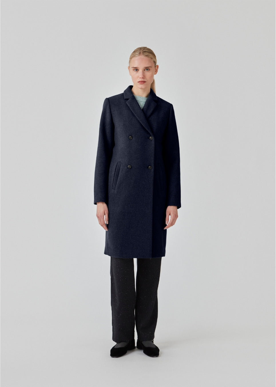 Smuk og klassisk knælang uldfrakke. Odelia coat i farven Navy Sky bliver lukket fortil af fire knapper og er taljeret, hvilket giver et feminint udtryk. På grund af den høje kvalitet af uld, vil den være det oplagte valg til både efterår og de milde vintre.
