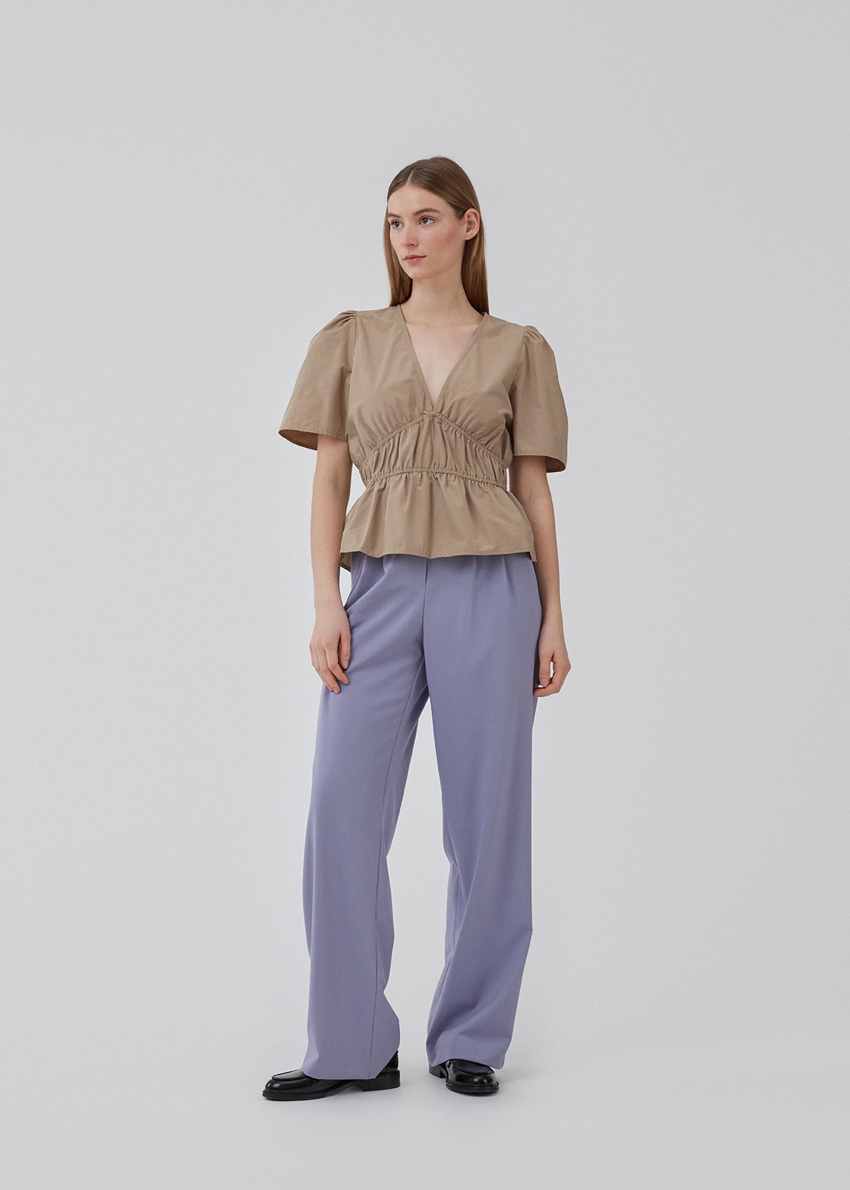 Top i beige i bomuldsblanding med korte ærmer med let puf og dyb v-udskæring i halsen. DeenMD top har flatterende rynkedetaljer under brystet og i taljen. Modellen er 177 cm og har en størrelse S/36 på.