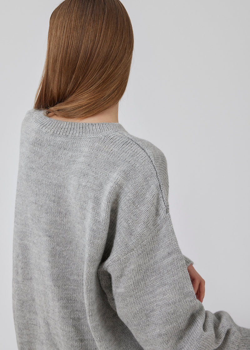 Oversized fluffy striktøje i grey melange af kvalitet med uld og alpaka. TalaMD o-neck har en rund hals, lav skuldersøm og en længere bagside. Ribstrikkede kanter på hals, ærmer og forneden.&nbsp;