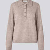 Strikket polo med lange ærmer. Treemd polo har en stolpelukning og 4 knapper.