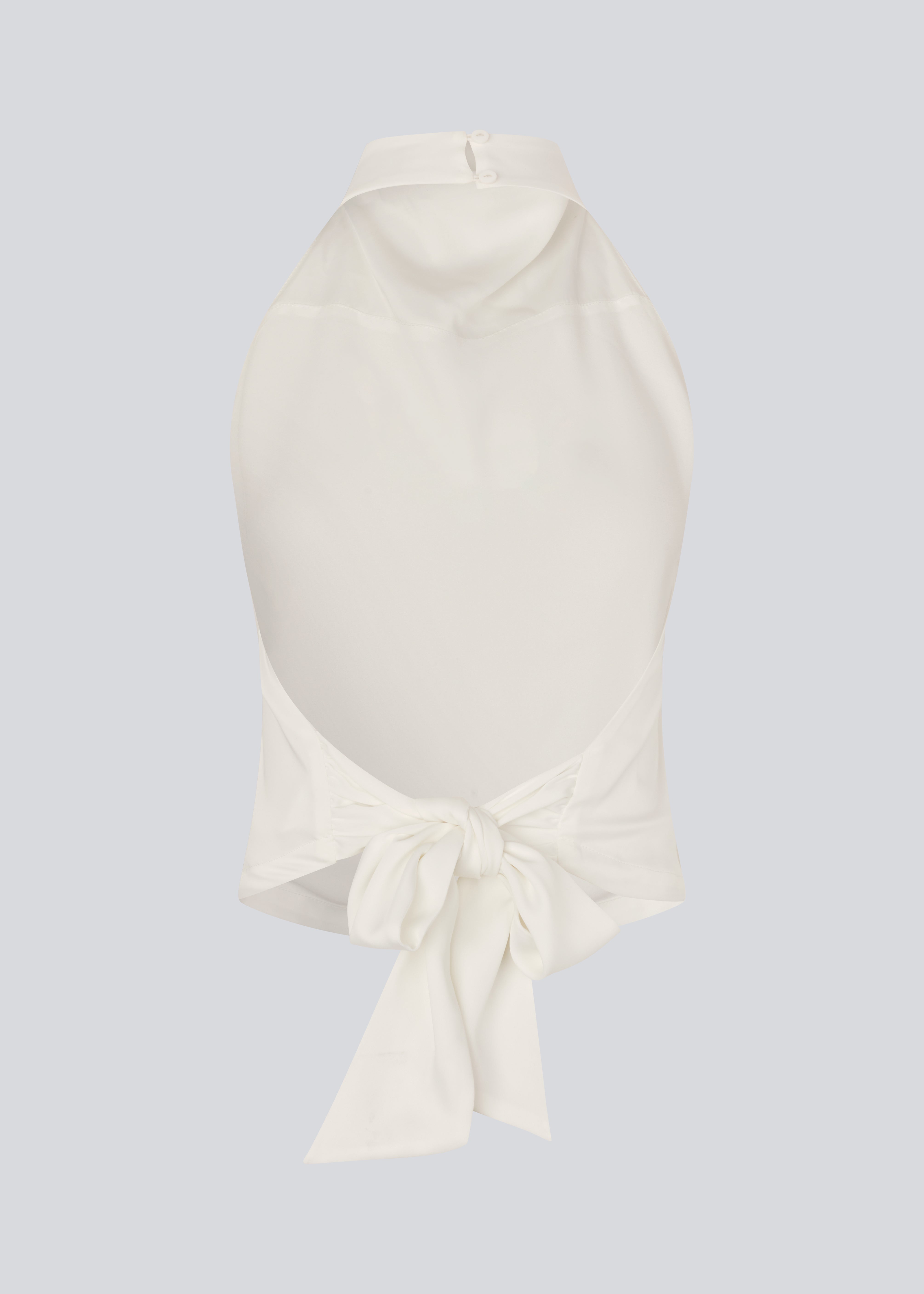 Halterneck top i hvid med bindedetalje i satin. Timmiemd top har en åbenryg med bindebånd og en knappelukning i nakken.&nbsp;