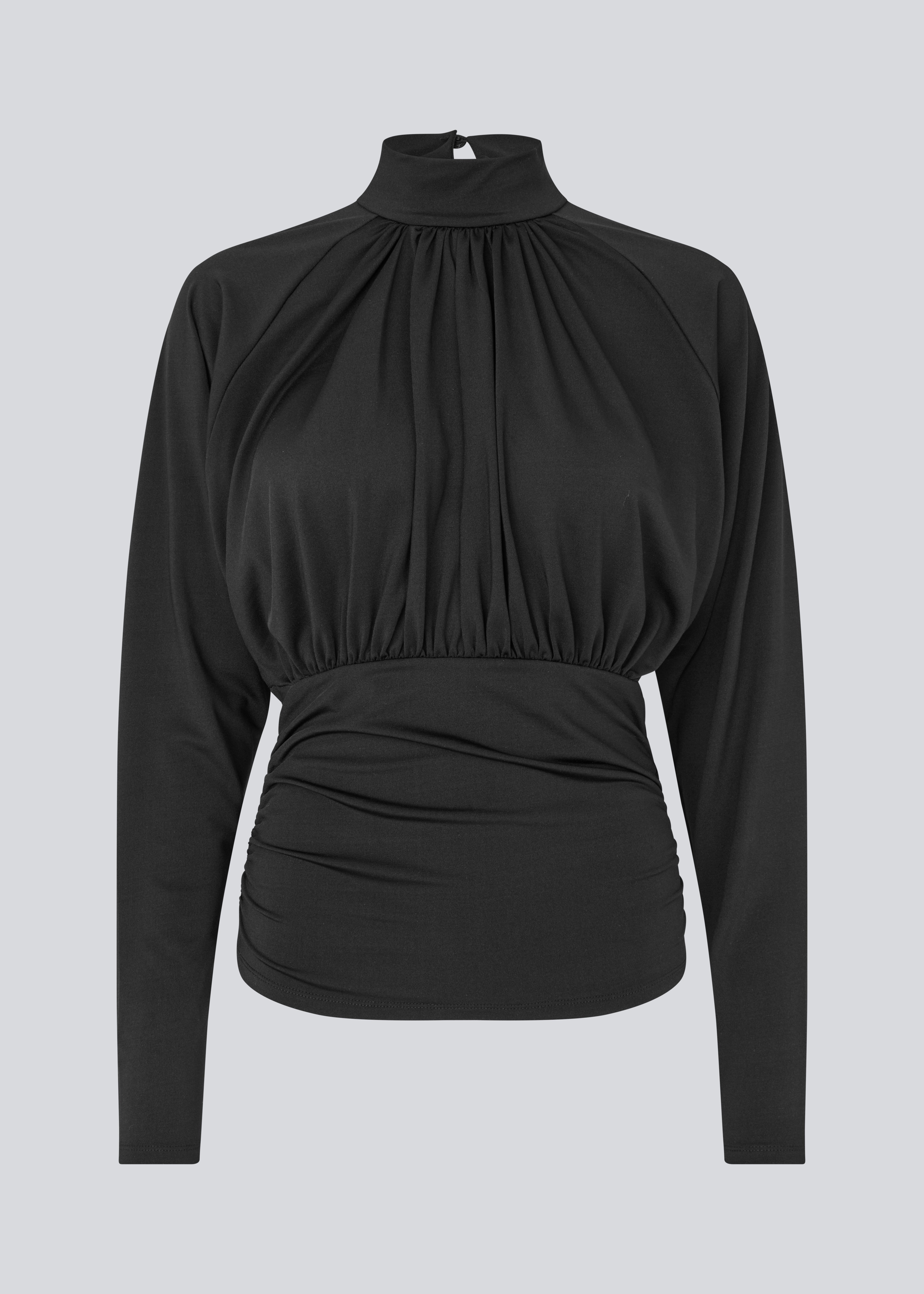 Elegant sort bluse med høj hals og lange ærmer. Blusen er designet med fine rynkedetaljer ved brystet og taljen, som skaber en flatterende silhuet. Den har en diskret knaplukning bagpå i nakken, som giver et sofistikeret og feminint udtryk. Det strækbare stof sikrer en behagelig pasform, mens det draperede snit tilføjer ekstra elegance. Perfekt til både hverdagsbrug og festlige lejligheder.