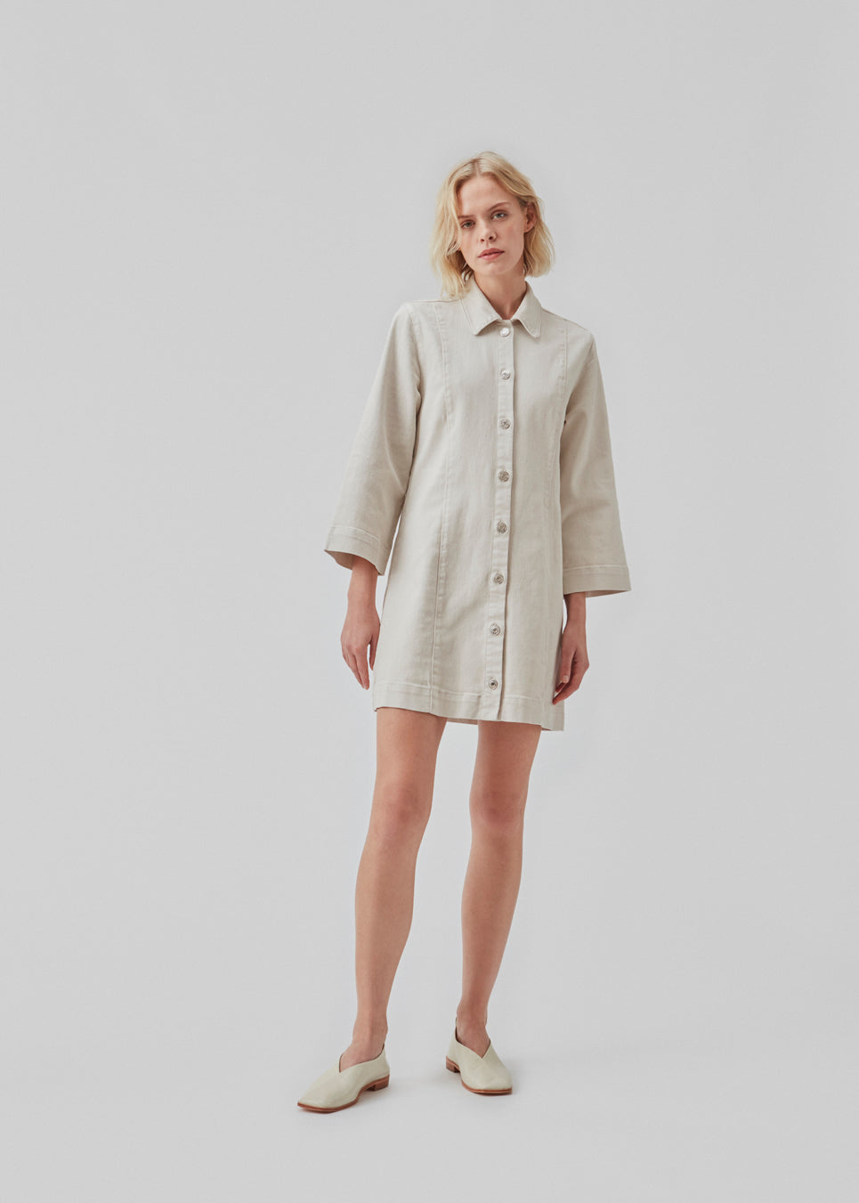 Kort denim kjole med en smule figursyet silhuet. ChikoMD dress har krave og knaplukning fortil og 3/4 lange, brede ærmer. Modellen er 177 cm og har en størrelse S/36 på.