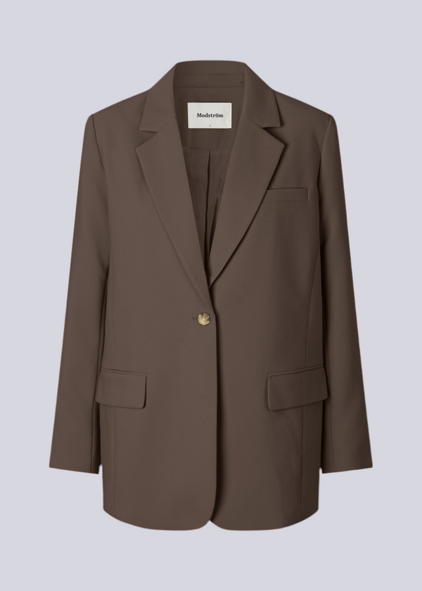Gale blazer i farven: Espresso brun har et klassisk og elegant design, som kommer til udtryk i den flotte reverskrave og den lange pasform. Blazeren har knaplukning fortil og en brystlomme i venstre side.

