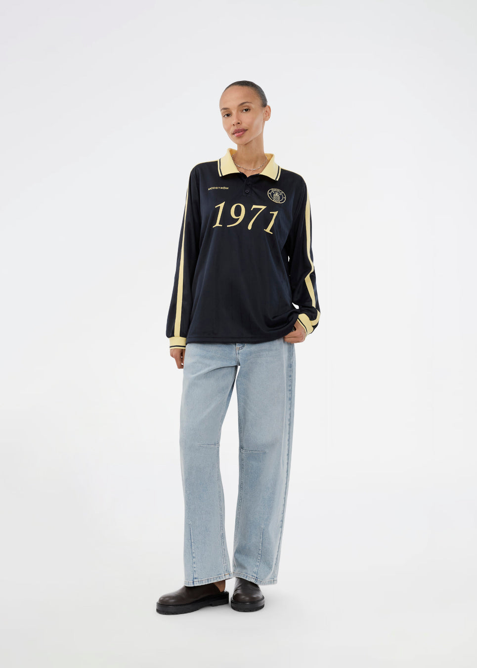 Fodbold jersey i mørkeblå med gule detaljer lavet i samarbejde med Brøndbys kvindehold. 1971 Polo har en løs pasform med stolpelukning og krave, samt lange ærmer med ribkant. Desuden har poloen Brøndby Womens og Modström logo på brystet.