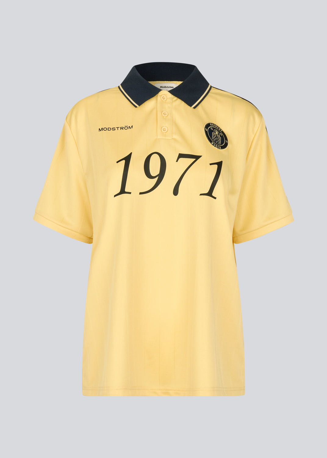 Fodbold jersey i gul med mørkeblå detaljer lavet i samarbejde med Brøndbys kvindehold. 1971 Polo har en løs pasform med stolpelukning, krave samt korte ærmer. Desuden har poloen Brøndby og Modström logo på brystet.

Poloen er unisex og skabt til både fans, fodboldelskere og dig der bare vil have et sporty look.