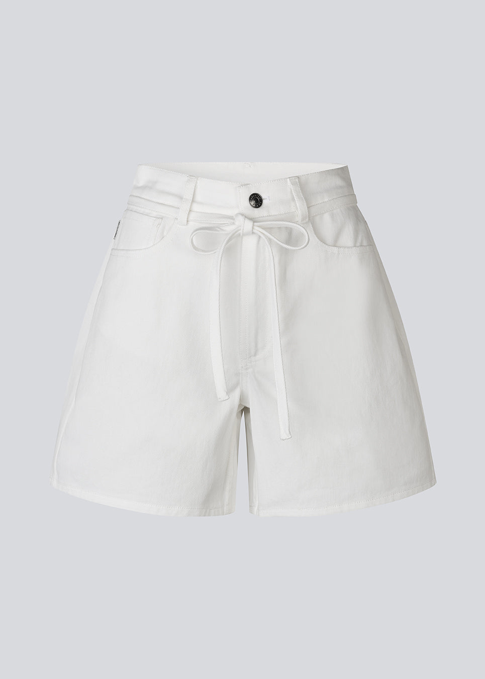 Stilrene shorts i hvid bomuldsdenim. AggiMD Solid Shorts er lange og har klassiske detaljer som lommer, bæltestropper, knap- og lynlåslukning i gylpen samt snørrebælte i taljen. Et moderne og afslappet valg til sommerens outfits.
