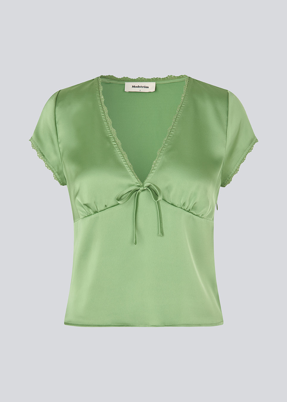 Feminin kortærmet top i glansfuld satin. AijaMD Top har fine detaljer som blondekanter, V-udskæring, let puf under brystet og sløjfedetalje. Fremstillet i 100% genanvendt polyester, perfekt til både elegante og afslappede looks.