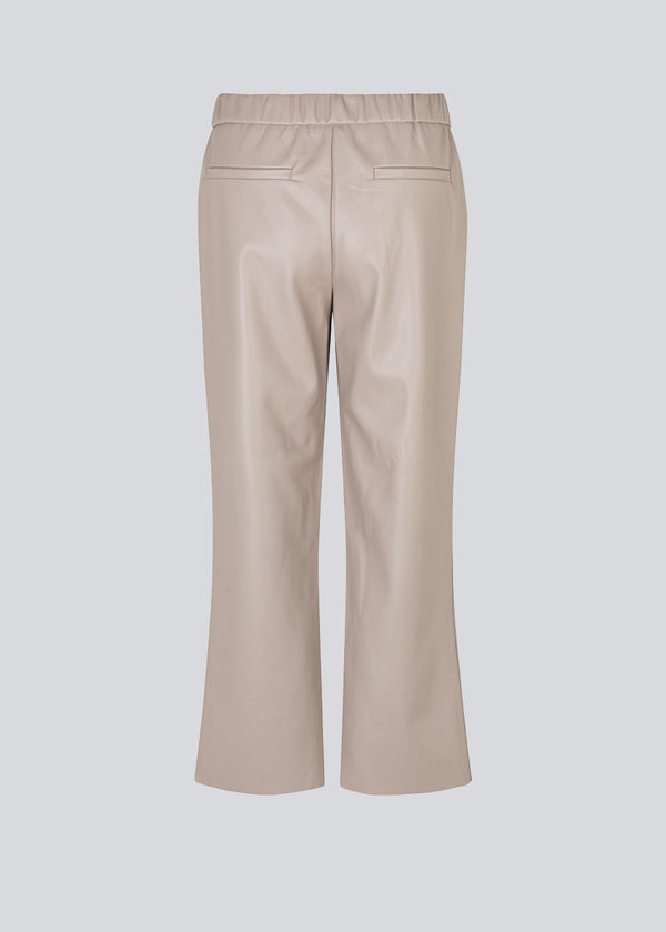 Ankellange bukser i beige med et afslappet fit i PU læder. AlmaMD pants har beklædt elastik i taljen og let svaj i benene.