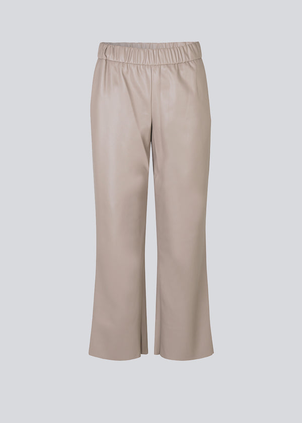 Ankellange bukser i beige med et afslappet fit i PU læder. AlmaMD pants har beklædt elastik i taljen og let svaj i benene.
