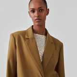 Oversized blazer i farven breen med blødt fald. AnkerMD blazer har krave og revers samt en knap foran. Forlommer med klap og brystlomme. Slids bagpå og ved ærmer. Med for.  Modellen er 177 cm og har en størrelse S/36 på. Style blazeren med matchende bukser i samme farve: AnkerMD pants.