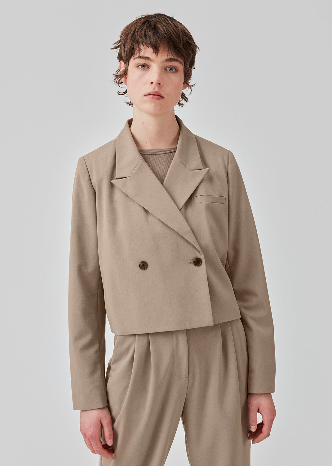 Kort, dobbeltraddet blazer med krave og spidsrevers i beige. AnkerMD short blazer har en lige pasform med to knapper og en dekorativ paspoleret brystlomme.