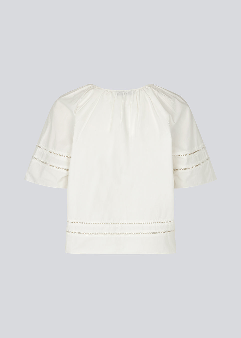 Kortærmet bluse med broderidetaljer. AyoMD Top har et løst snit og rynkedetaljer ved halsen samt V-udskæring med enkel knap. Toppen er fremstillet i et let materiale i 100% økologisk bomuld, perfekt til et feminint og afslappet look.