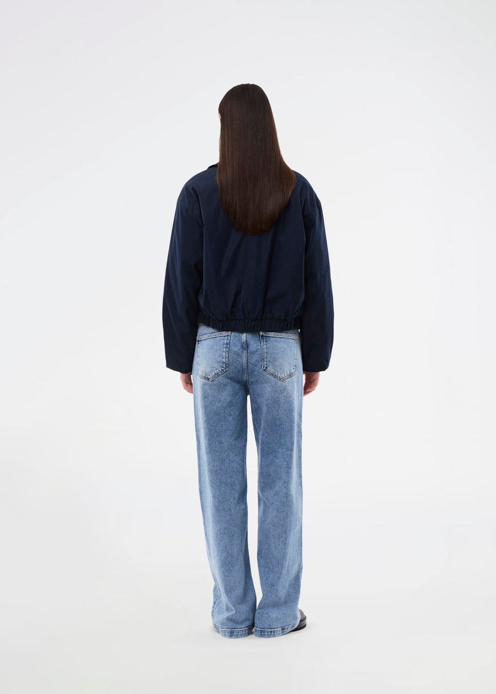 Moderne og funktionel jakke. Badumd jacket er designet med klassisk krave, skjult lukning og elastisk kant, der skaber en afslappet, let cropped silhuet. En stilren overgangsjakke, der kombinerer et minimalistisk udtryk med komfort og alsidige stylingmuligheder.