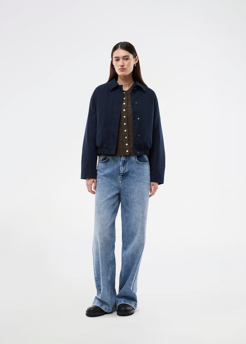 Moderne og funktionel jakke. Badumd jacket er designet med klassisk krave, skjult lukning og elastisk kant, der skaber en afslappet, let cropped silhuet. En stilren overgangsjakke, der kombinerer et minimalistisk udtryk med komfort og alsidige stylingmuligheder.