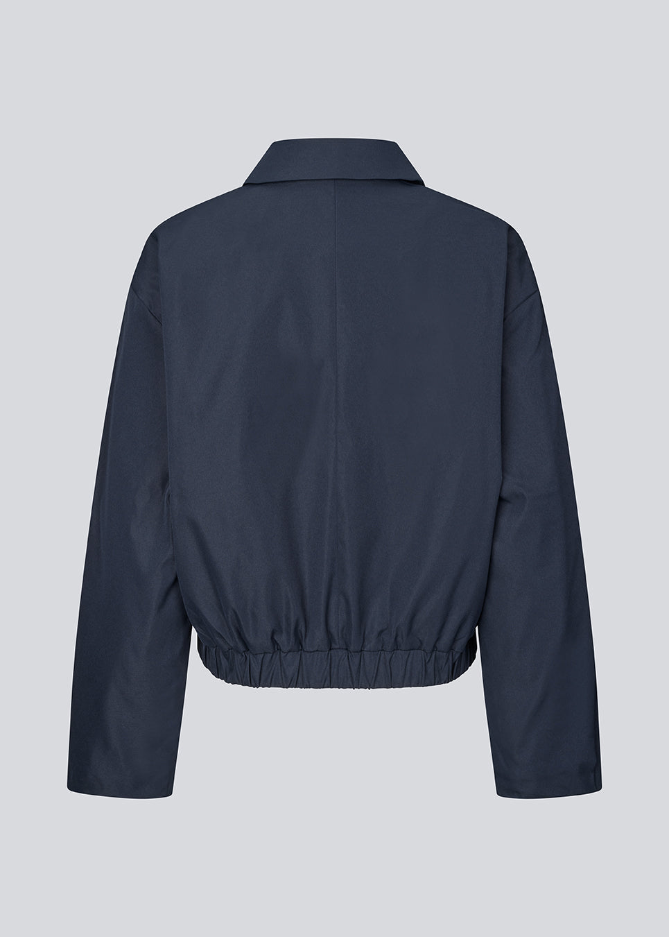 Moderne og funktionel jakke. Badumd jacket er designet med klassisk krave, skjult lukning og elastisk kant, der skaber en afslappet, let cropped silhuet. En stilren overgangsjakke, der kombinerer et minimalistisk udtryk med komfort og alsidige stylingmuligheder.