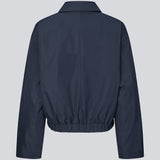 Moderne og funktionel jakke. Badumd jacket er designet med klassisk krave, skjult lukning og elastisk kant, der skaber en afslappet, let cropped silhuet. En stilren overgangsjakke, der kombinerer et minimalistisk udtryk med komfort og alsidige stylingmuligheder.