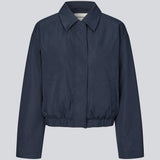 Moderne og funktionel jakke. Badumd jacket er designet med klassisk krave, skjult lukning og elastisk kant, der skaber en afslappet, let cropped silhuet. En stilren overgangsjakke, der kombinerer et minimalistisk udtryk med komfort og alsidige stylingmuligheder.