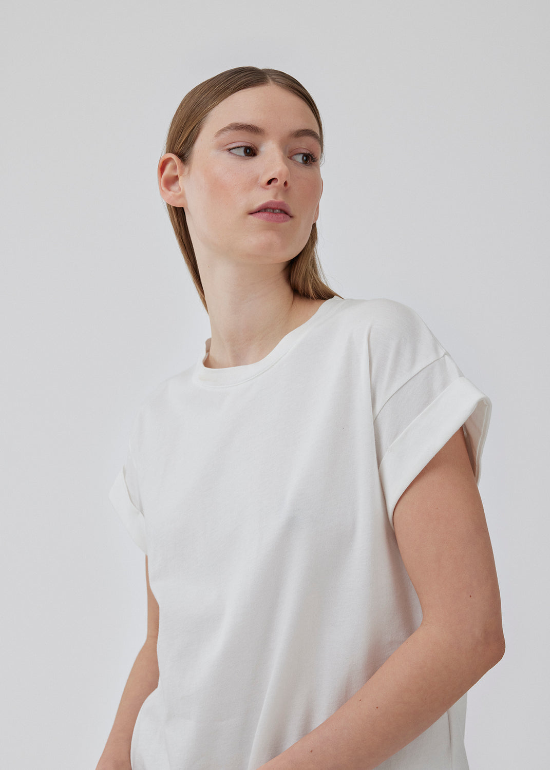 Hvid t-shirt i økologisk bomuld med en smule kortere længde. BrazilMD short t-shirt har rund hals og opsmøgede ærmer. Modellen er 177 cm og har en størrelse S/36 på.<br>