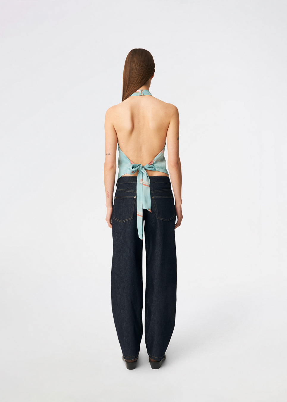 Elegant halterneck-top med et kunstnerisk print og et feminint udtryk. Carinamd print top er designet i en let, glat kvalitet med en høj halterneck-udskæring, der lukkes i nakken, og et bindebånd i ryggen, som giver en smuk og justerbar pasform. Det draperede design og det unikke print gør toppen til et iøjnefaldende valg til både festlige lejligheder og sommerens elegante outfits.